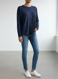 A navy plus size top with distressed slashing panels displayed on a hanger against a white background.