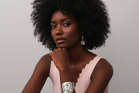 Woman wearing a silver bracelet and earrings against a plain background