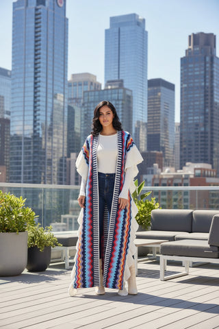 Woman wearing a long, colorful striped cardigan with a white top and jeans on a white background