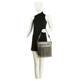 Mannequin wearing a black dress holding a silver fringe handbag on a white background