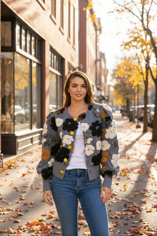 Woman wearing a floral-patterned jacket with colorful buttons on a white background