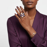 Woman wearing a floral ring and bracelet on a plain background