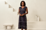 Woman wearing a black dress with white geometric patterns on a staircase.