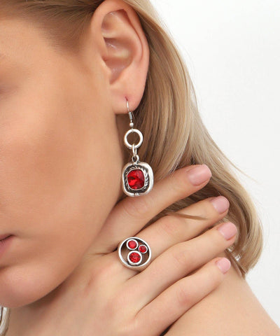 Close-up of a woman wearing silver earrings with red gemstones on a white background