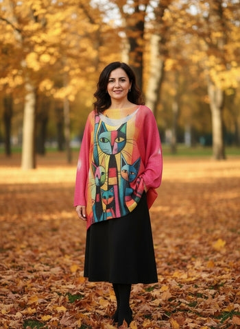 Colorful cat-patterned shirt on a hanger against a white wall