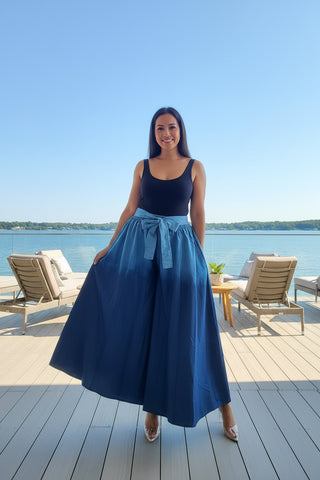 Person wearing blue wide-leg denim pants and a black top in a room with decor elements.