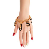 Hand wearing a gold chain bracelet with black accents on a white background
