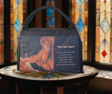 Black bag with a design and text on a table in front of stained glass windows