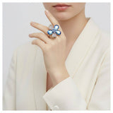 Close-up of a hand wearing a decorative ring with blue gemstones on a white background
