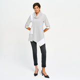 Woman wearing a black and white striped shirt with a white top and black pants on a white background