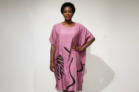 Pink dress with black graphics on a hanger against a white background