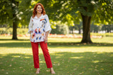 White blouse with colorful floral and cat print on a hanger