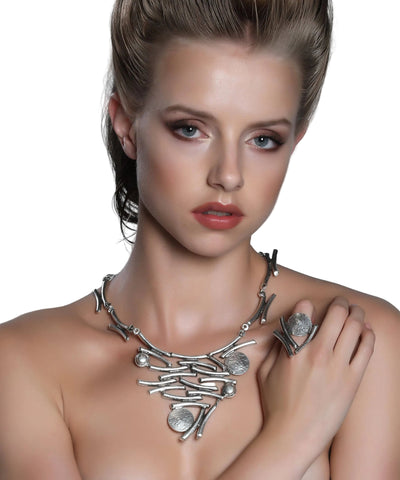 Woman wearing a silver necklace with a gray background