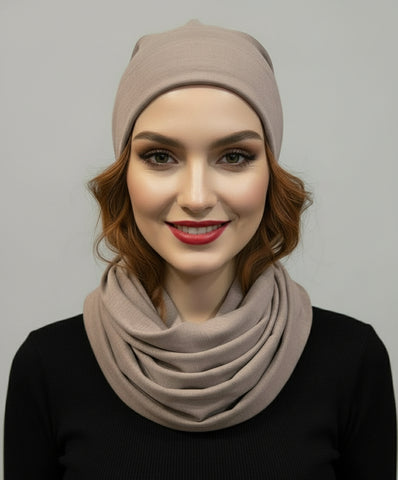 Mannequin head wearing a beige beanief and scarf on an orange background