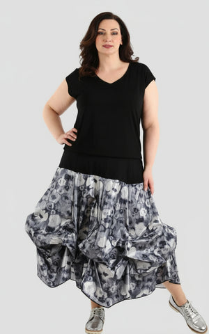 Woman wearing a black sleeveless top and a bubble skirt hem dress in navy and white floral design. 