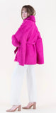 Woman wearing a bright pink coat with fur trim on a white background