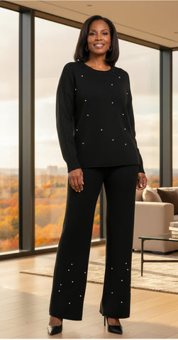 Woman wearing a knit black outfit with white pearl embellishments on a white background