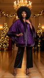 Woman wearing a purple sequin cape with fur trim on a white background