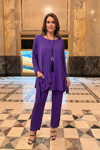 Purple pantsuit outfit on a mannequin against a decorative wall.
