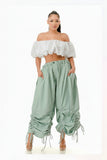 Woman wearing a white off-shoulder top and light blue ruffled pants on a white background