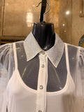 White blouse with a sparkling collar on a mannequin against a reflective surface.