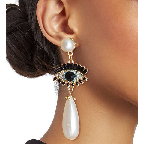 Earring with a decorative design and pearl-like stone worn by a person.