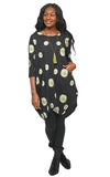 Woman wearing a black dress with green floral patterns on a white background