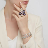 Close-up of a hand wearing a floral ring and bracelet on a plain background