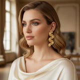 Woman wearing gold earrings in a softly lit room