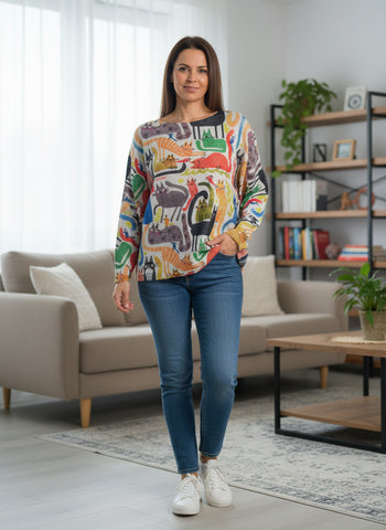 Colorful sweater with cat pattern on a hanger against a white wall