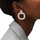 Close-up of an ear wearing a large, round, pearl-like earring with a blurred background.