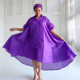 Woman wearing a purple dress with a hood in a bright room.
