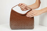 Brown handbag with rhinestone embellishments on a white background
