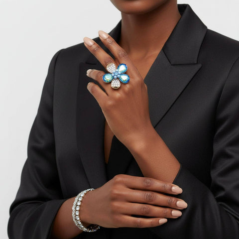 Person wearing a black blazer with a decorative ring and bracelet on a neutral background